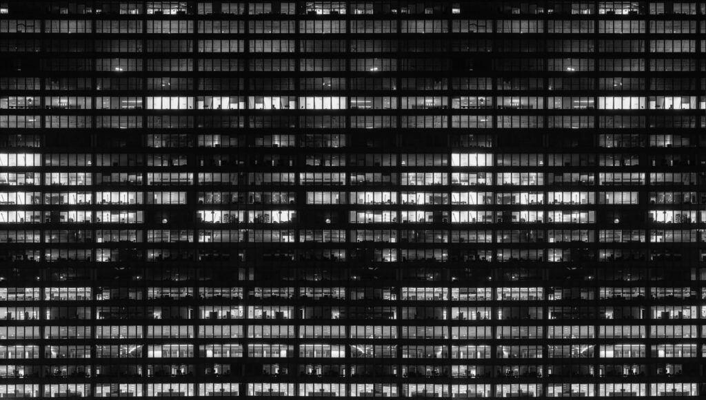 vue sur un immeuble impressionnant, tous les appartements illuminés ou non sont comme un puzzle, vue de nuit, photo noir et blanc